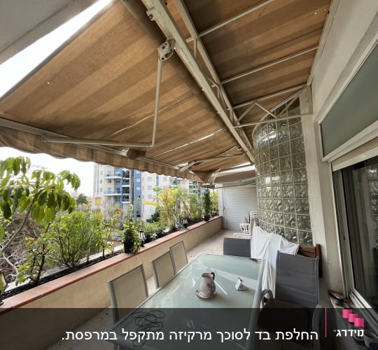 סוככים חומים נפתחים מעל מרפסת עם שולחן זכוכית